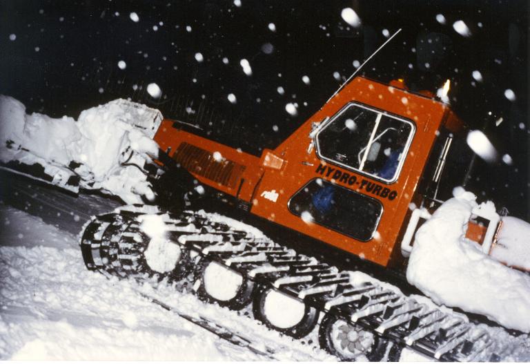 Vue d'une dameuse, de nuit, sous la neige